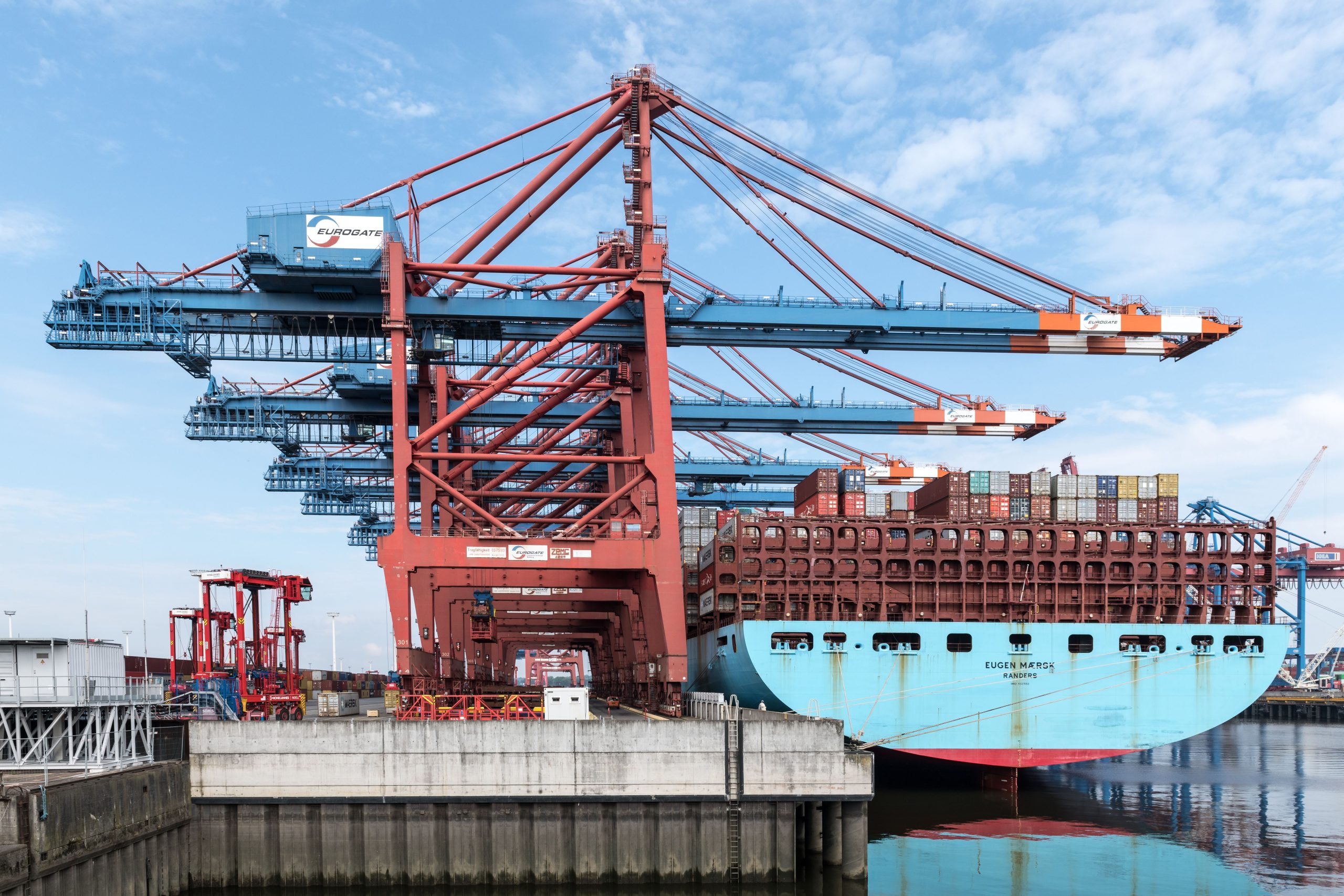 A cargo ship docked at the Port of Hamburg with cranes loading containers.